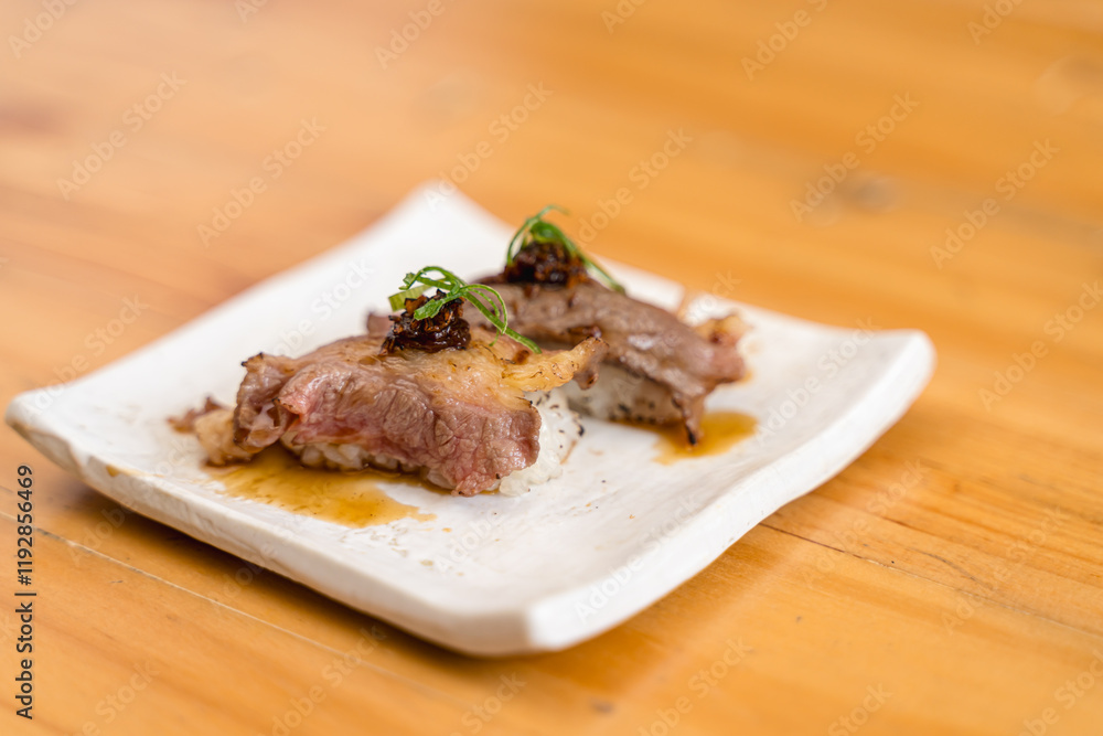Wagyu beef sushi garnished with herbs and sauce, served on a minimalist white ceramic plate. Wagyu beef sushi garnished with herbs and sauce, served on a minimalist white ceramic plate.