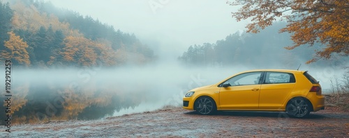 A yellow hatchback car with foggy windows parked near a lake on a misty morning, capturing serenity