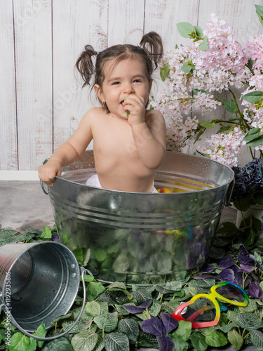 A little girl playing in a copper bathtub or bathing basin with a retro design, surrounded by rubber bath toys. A playful and cozy scene evoking childhood memories.
 photo