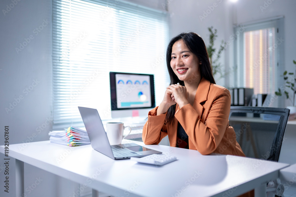 A woman is sitting at a desk with a laptop and a cup of coffee A woman is sitting at a desk with a laptop and a cup of coffee