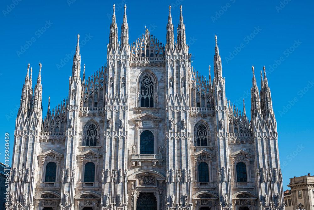 Fototapeta premium View of the Milan Cathedral. Duomo di Milano. Overview of the facade of the cathedral in white marble. Buttresses, pinnacles and spiers. Statue of the Madonnina. Lombardia