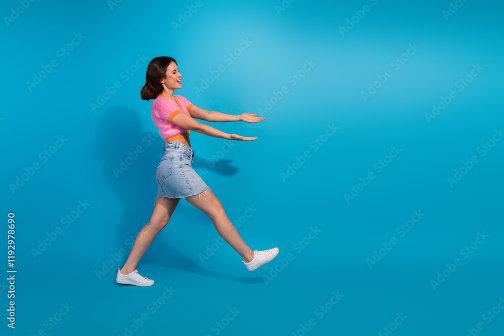Smiling young woman walking in style against a blue background with casual summer fashion Smiling young woman walking in style against a blue background with casual summer fashion