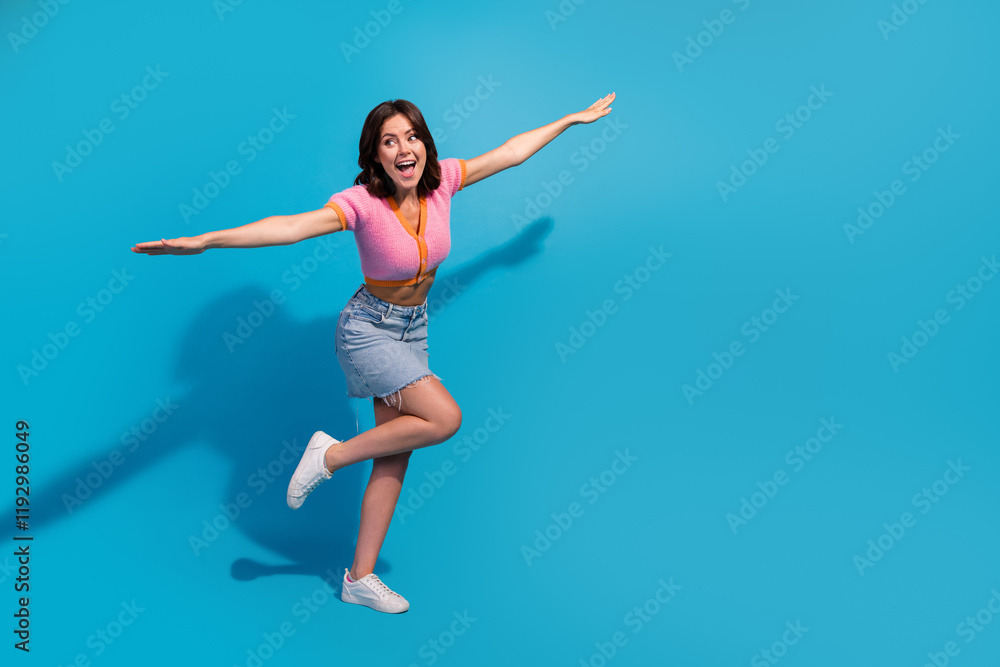 Joyful young woman playfully posing against a vibrant blue background showcasing casual fashion and summer style Joyful young woman playfully posing against a vibrant blue background showcasing casual fashion and summer style