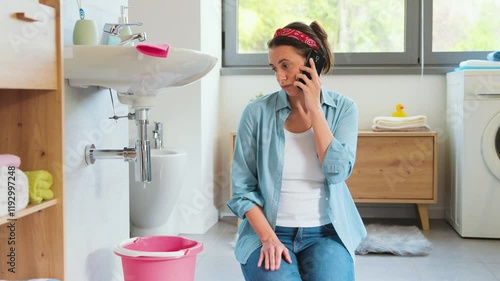 Disappointed woman calling a plumber at home