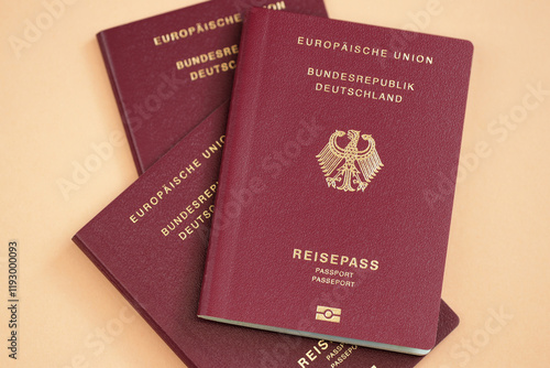 Three German passports on orange background, close-up shot. Symbol of German citizenship, naturalization, travel, freedom of movement, documentary legitimacy, immigration, Germany and EU membership. photo