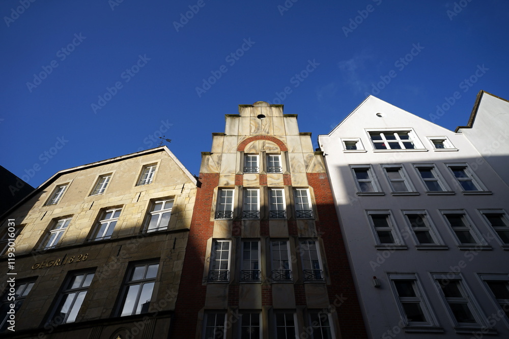 Fototapeta premium Schöne restaurierte Giebelhäuser mit Spitzgiebel und Treppengiebel vor blauem Himmel im Sonnenschein in der City und Altstadt von Münster in Westfalen im Münsterland