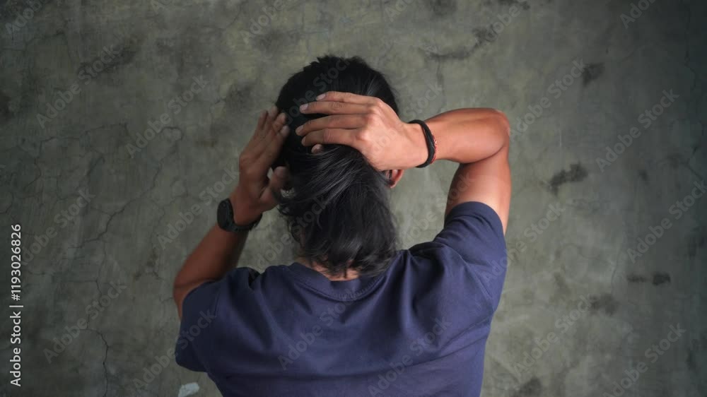 asian men tying hair in ponytail. asian male with brown skin tone and medium long hair doing pony tail hair bun