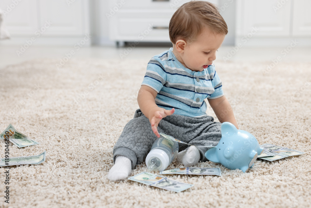 Little baby with bottle, money and piggybank on floor at home Little baby with bottle, money and piggybank on floor at home