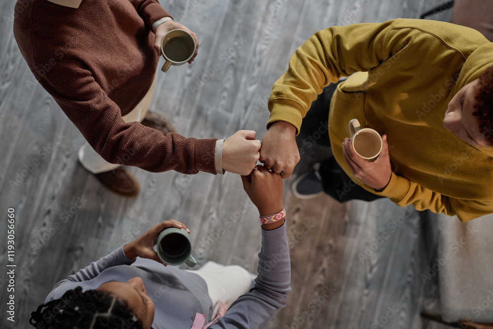 Fototapeta premium Top down view at three teenagers doing fist bump standing in circle showcasing bonding friendship and leadership copy space