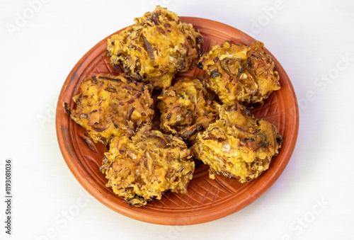 Crispy pakora on a clay plate, isolated on a white background. These delicious, deep-fried fritters are a popular snack or appetizer in Bangladesh, India, and other parts of South Asia. photo