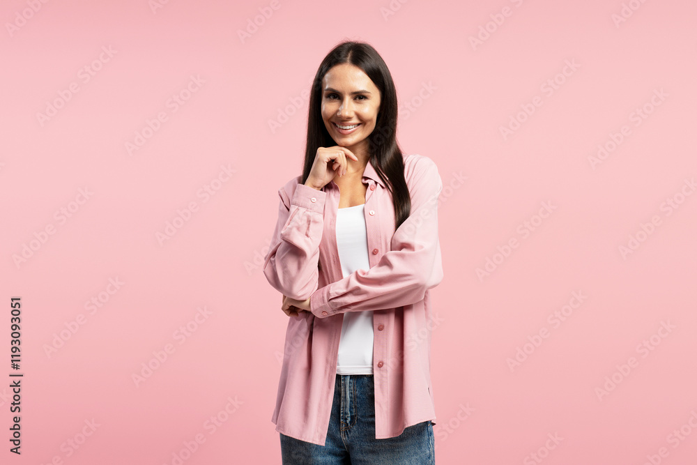 Smiling, middle aged, Hispanic woman smiling and touching chin on pink background looking at camera Smiling, middle aged, Hispanic woman smiling and touching chin on pink background looking at camera
