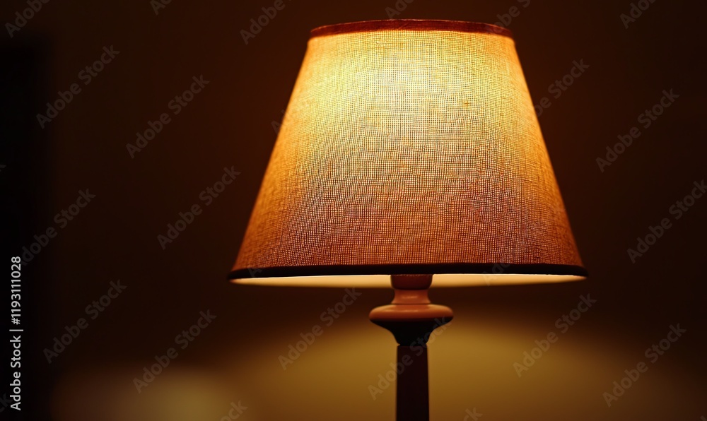 Lit lampshade on wooden stand in dark room, creating warm ambiance, ideal for home decor. Lit lampshade on wooden stand in dark room, creating warm ambiance, ideal for home decor.