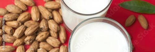 A close-up shot of almonds with a glass of almond milk on a vibrant red background, fresh, flavorful photo