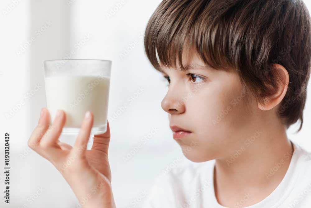 Cute boy doesn't want to drink milk from a glass at home Cute boy doesn't want to drink milk from a glass at home