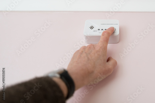 Bild auf Leinwand Homeowner seen doing a weekly test for an installed generic Carbon Monoxide located in a kitchen which uses gas appliances and central heating