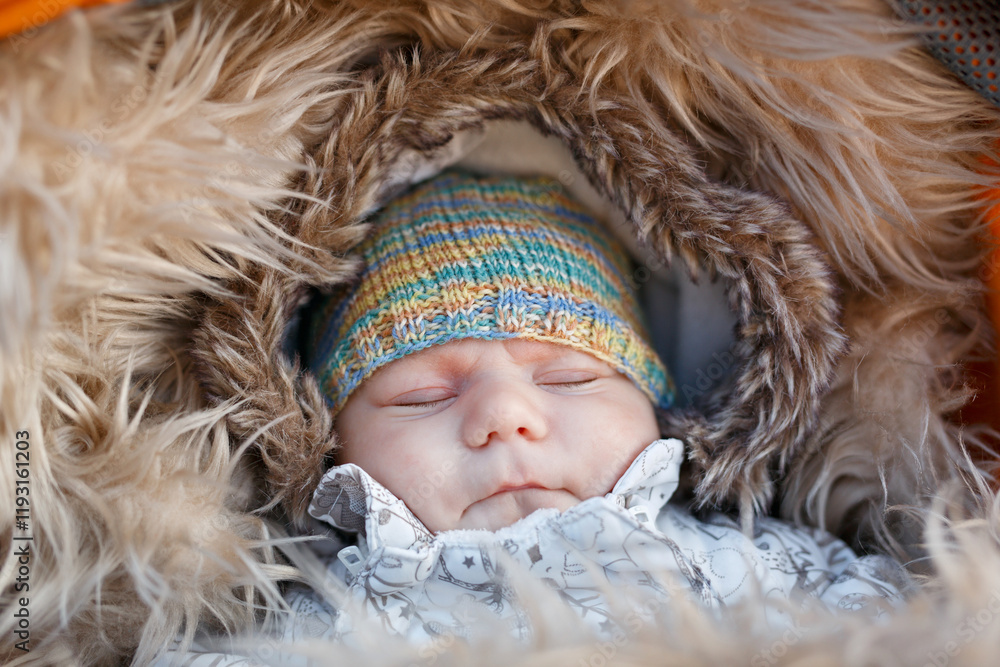 Portrait of newborn baby in warm winter clothes. Beautiful cute girl in warm overall, cap. Peaceful child sleep during outdoor walk.