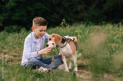 A boy shares ice cream with his beloved beagle dog. Concept of summer time, friendship, care and trust