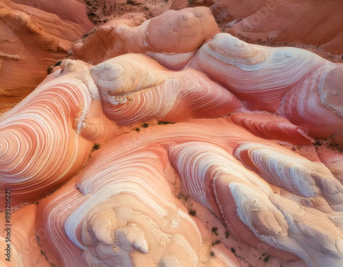 A breathtaking aerial photograph showcasing swirling, colorful sandstone formations, characterized by vibrant red and orange hues with smooth, flowing patterns.
