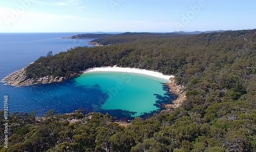 Aerial drone footage taken from a high angle provides a sweeping view of Freycinet Peninsula and National Park, featuring the celebrated Wineglass Bay in Tasmania, Australia. In the background, Mount photo