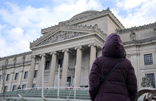 woman in winter coat jacket looking at brooklyn museum in prospect heights new york city (cold weather hood) travel tourism art history historic landmark eastern parkway nyc institution from behind photo