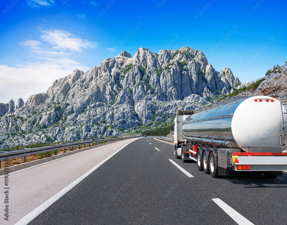 Fuel truck on a picturesque road. A silver tank truck transports fuel.