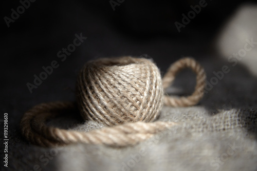 Still life a ball of linen threads and a small linen rope on burlap (linen fabric) 