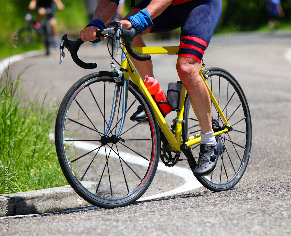 legs of cyclist pedaling energetically on the yellow racing bicycle during the race