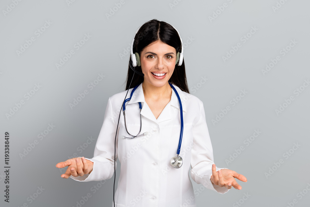 Smiling female doctor with headset and stethoscope wearing lab coat on a grey background Smiling female doctor with headset and stethoscope wearing lab coat on a grey background