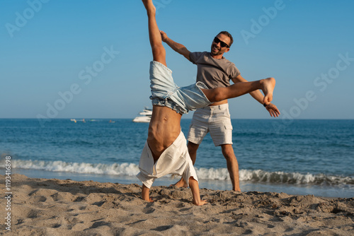 Father and Son Playing and Doing Cartwheels on the Beach photo