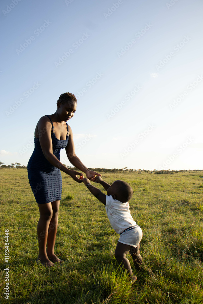 A beautiful young African woman playing with her baby boy outdoors at sunset A beautiful young African woman playing with her baby boy outdoors at sunset