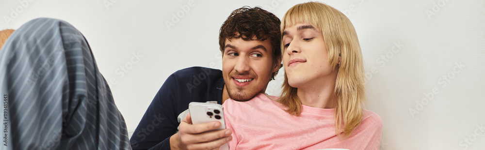 Couple smiles and laughs on the couch, enjoying a show together on their phone. Couple smiles and laughs on the couch, enjoying a show together on their phone.