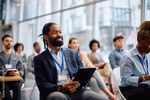 Happy black businessman using touchpad during seminar in board room. photo