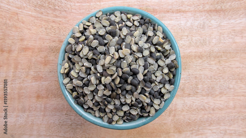 Flat Lay of Split Black Gram Black Lentil (Urad Dal, Vigna Mungo) in a Bowl on Neutral Wooden Background Flat Lay of Split Black Gram Black Lentil (Urad Dal, Vigna Mungo) in a Bowl on Neutral Wooden Background