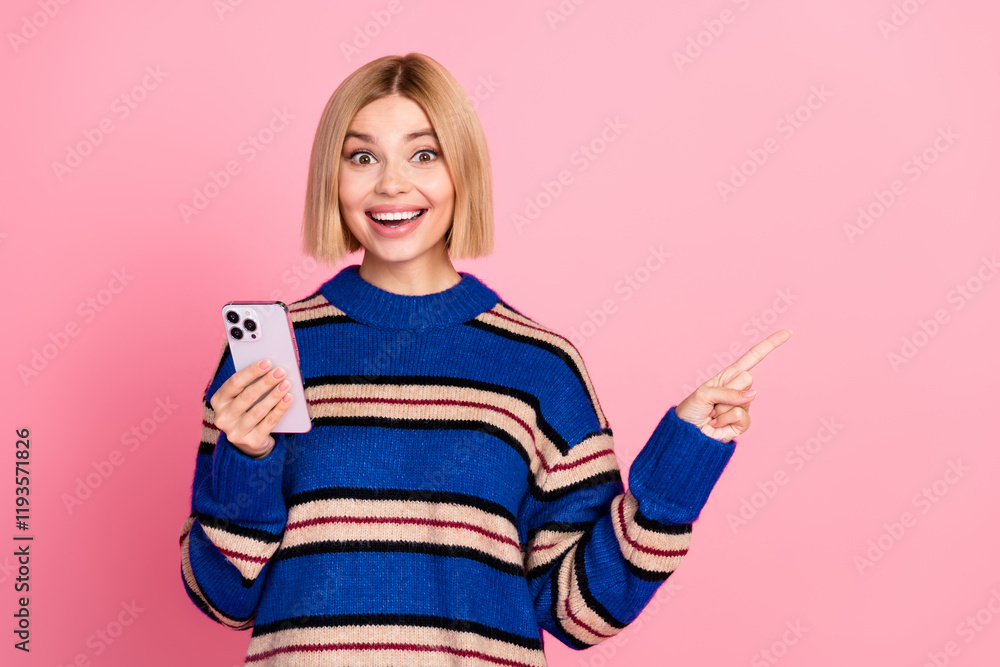 Smiling young woman presenting a point while holding a smartphone against a pink background Smiling young woman presenting a point while holding a smartphone against a pink background