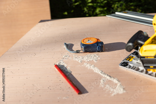 Male using ruler to measure board before cutting using an electric saw photo