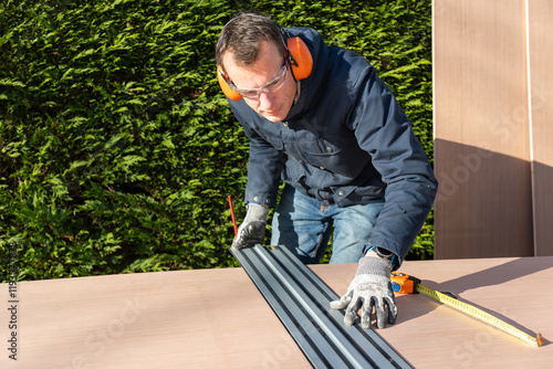 Male using ruler to measure board before cutting using a electric saw photo