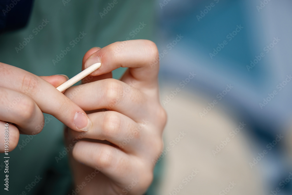 woman's hands gently pushing back cuticles using an orange wood stick during a manicure, showcasing nail care and beauty treatment techniques woman's hands gently pushing back cuticles using an orange wood stick during a manicure, showcasing nail care and beauty treatment techniques