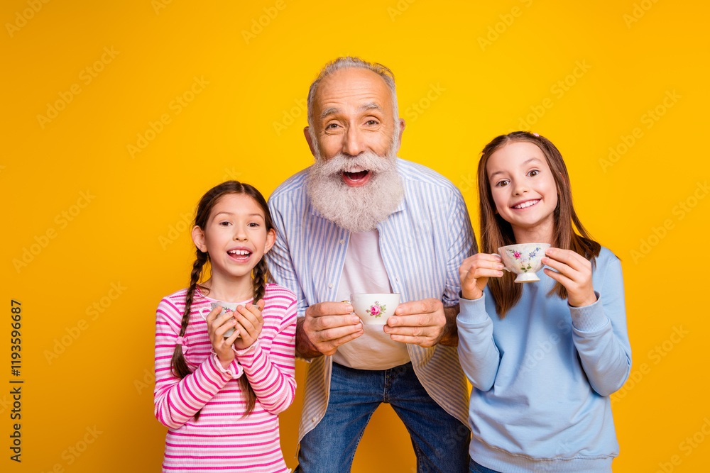© deagreez - Cheerful grandfather and granddaughters enjoying together with tea cups against a vibrant yellow backdrop © deagreez - Cheerful grandfather and granddaughters enjoying together with tea cups against a vibrant yellow backdrop