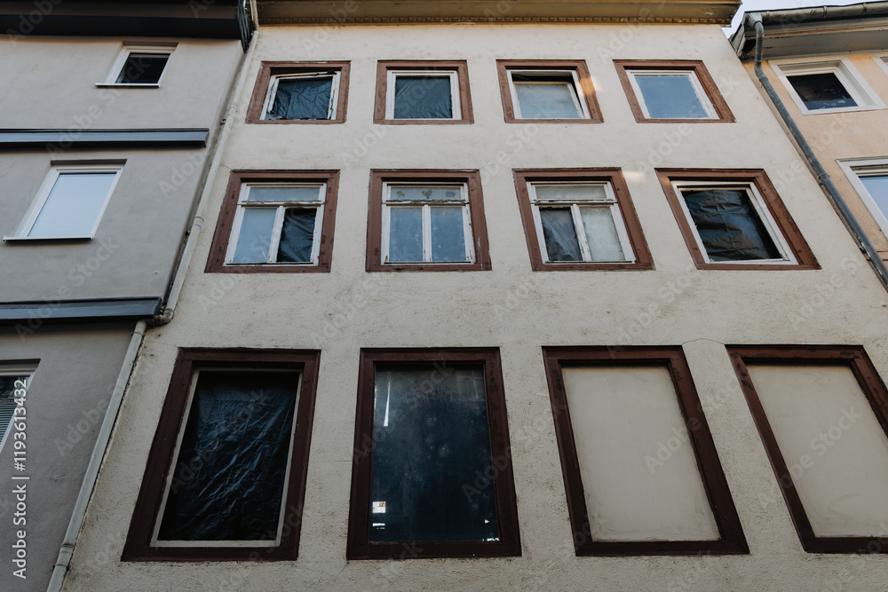 Fototapeta premium Abandoned building with multiple windows and an unsettling atmosphere in a quiet urban area