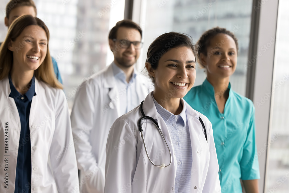 Group of diverse doctors, clinic staff posing together led by Indian woman in white lab coat, smile, look into distance with confident expression, exude leadership, professionalism in healthcare field Group of diverse doctors, clinic staff posing together led by Indian woman in white lab coat, smile, look into distance with confident expression, exude leadership, professionalism in healthcare field