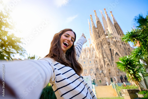 Young funny caucasian women taking a selfie in front of Sagrada Familia in Barcelona. Smiling beautiful girl on street of European city enjoying vacation happy and smiling. Funny tourism people