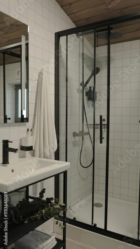 Vertical video. This modern bathroom showcases a stylish shower and an elegant sink that enhances the space
