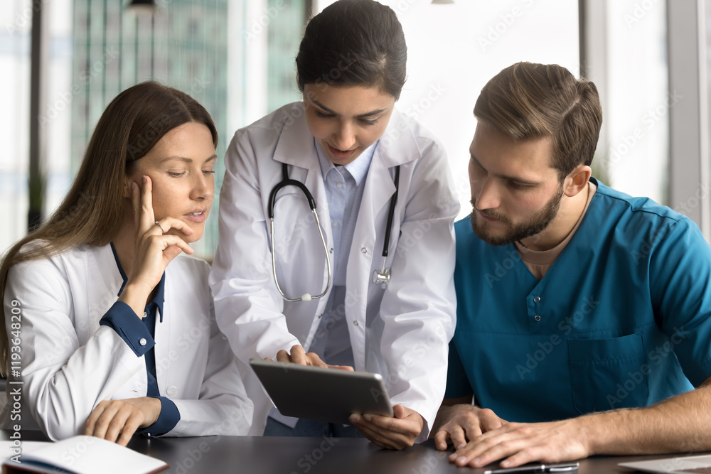 doctors examining information on tablet, at meeting in clinic led by Indian GP, explaining new apps, showing patient data, analyzing medical images such as x-rays or scans, discussing treatment plans doctors examining information on tablet, at meeting in clinic led by Indian GP, explaining new apps, showing patient data, analyzing medical images such as x-rays or scans, discussing treatment plans