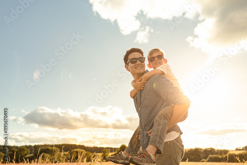 father and son in the park. father's day happy family child dream concept. father carries his son on his back. dad playing with his son in nature in the park at sunset lifestyle photo