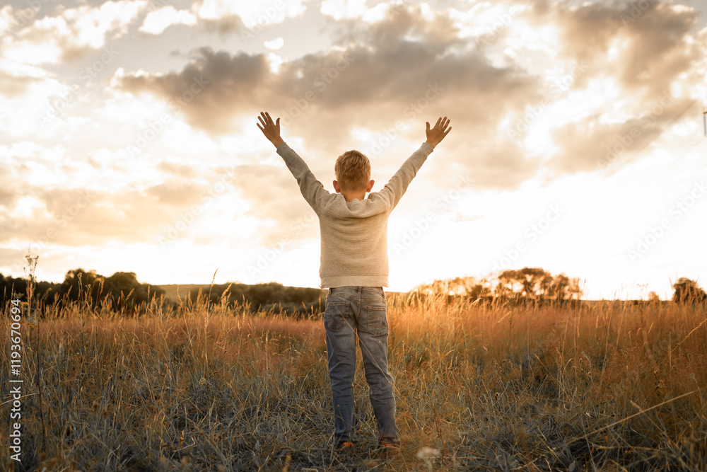 It's a beautiful life! Happy child standing in a field at sunset having feelings of freedom, hope, and happiness It's a beautiful life! Happy child standing in a field at sunset having feelings of freedom, hope, and happiness