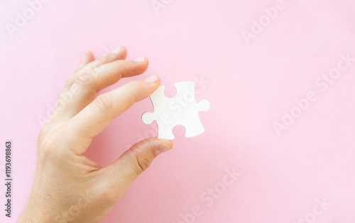 Hand holding white piece of jigsaw puzzle, top view photo