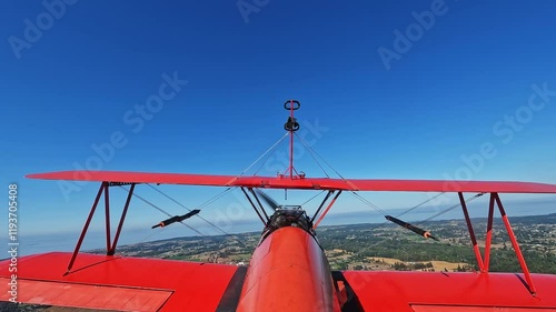 Red Biplane Flying Over Landscape Captured from Tail View