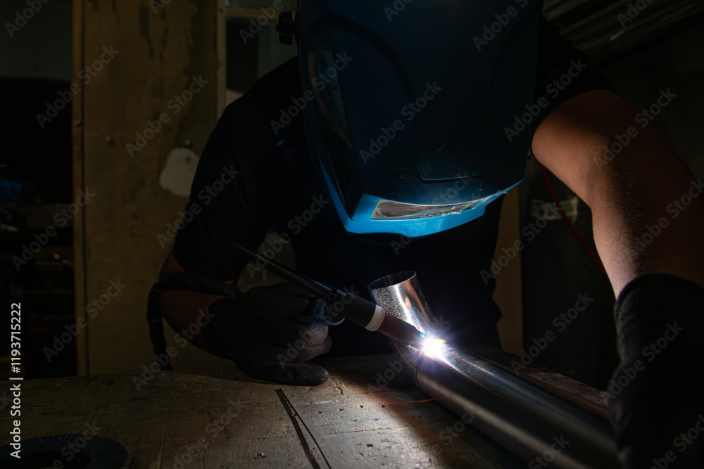 Operator Using TIG Torch to Weld Metal Tube with Safety Gear Operator Using TIG Torch to Weld Metal Tube with Safety Gear