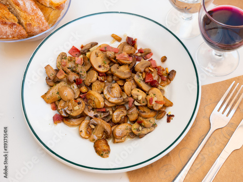 Sauteed Mushrooms served on white plate with glass of wine photo