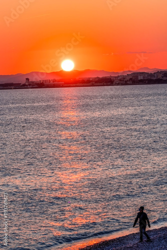 People Watching Sun Go Down Beach reflection Mediterranean Sea Coastline Seacoast, Nice, Cote d'Azur, France photo